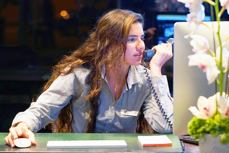 Hotel administrator. A woman-reception worker accepts an order for booking a room by phone. Profile shot of attractive executives at the reception of a hotel. The concept of service.の写真素材