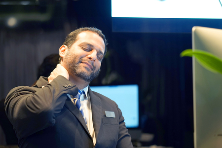 Tired Neck. Hotel manager. A men-reception Suffering From Neck Pain. Bearded man. Male Feeling Tired, Exhausted, Stressed. Men Massaging Painful Neck With Hands. Body And Health Care Concept.の写真素材
