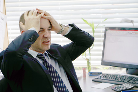 A man in stress in front of a computer. Poor economy concept. Face expression, emotion. Body And Health Care Concept.の写真素材