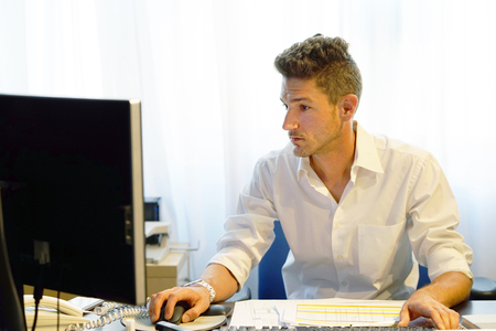 Man Working At Desk In Busy Creative Office. Office worker man at the computer.の写真素材