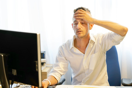 Close-up office worker Men Suffering From Headache Sitting In Front Of Computer. Body And Health Care Concept.の写真素材