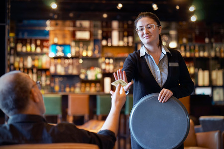 The waitress refuses to receive a tip from the client in the hotel bar. The girl is frustrated. Emotions. The concept of service.の写真素材