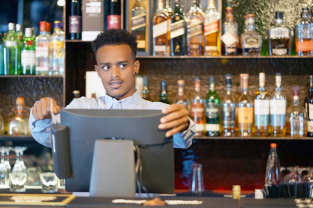 Registration male of bartender employee of a new order by a cash register. The barman pays the order with a credit card. Service concept. Close-up.の写真素材