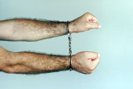 Close-up. Arrested man handcuffed hands. Prisoner or arrested terrorist, close-up of hands in handcuffsの写真素材