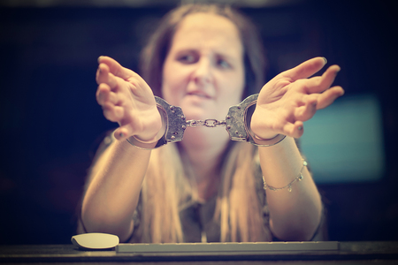 Arrested woman handcuffed hands. Close-up of office worker, Prisoner or arrested terrorist, hacker, bribetaker, close-up of hands in handcuff. Selective focus. Toningの写真素材
