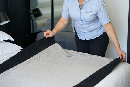 Maid making bed in hotel room.の写真素材