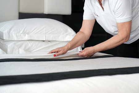 Maid making bed in hotel room.の写真素材