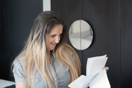 Woman enjoying good news in writing. The girl reads a letter with good news. An euphoric girl is happy after reading good news in a written letter, approving a loan.の写真素材