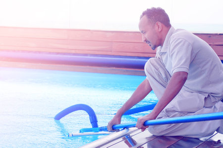Pool cleaner during his work. Hotel staff worker cleaning the pool. Toning.の写真素材