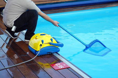 Pool cleaner during his work. Cleaning robot for cleaning the botton of swimming pools. Hotel staff worker cleaning the pool.の写真素材
