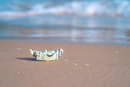 A boat made of paper money in the sea sand A boat out of the dollar in the sea. Sea sand. Concept for the dollar.の写真素材