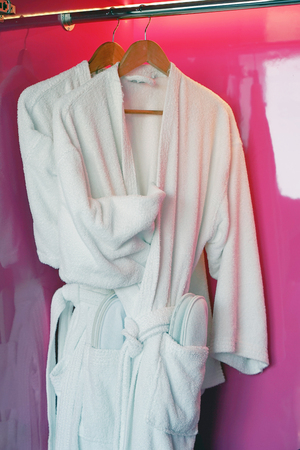 Two white coats hanging on the door. Hotel dressing gowns on the door hanger.の写真素材