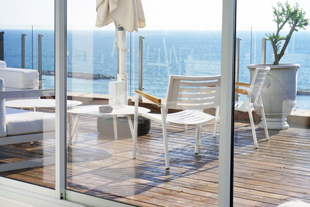 Interior of a large hotel balcony, villas. Beautiful balcony with white divans. White interior concept of a large balcony balcony. White color view of the morning horizon of the sea, the ocean.の写真素材