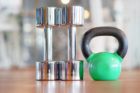 Green kettlebell and two chrome dumbbell on the floor in the gymの写真素材