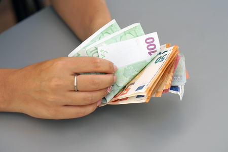 Woman hands that consider 100, 50-euro bills. In the hands of a lot of money, denominations of euros. Businesswoman hands hold and counting euro banknotes.の写真素材