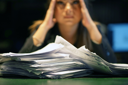 Close-up of office worker is distressed with a lot of paperwork in front of her. A lot of paper work in office. Yelling and screaming for bad results. Businesswoman in problems.の写真素材