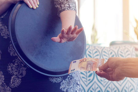 The hand of the waitress does not take the tip. The waitress refuses to receive a tip from the client in the hotel bar. The girl is frustrated. The concept of service. Toningの写真素材