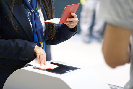 The stewardess checking the documents for boarding the plane at the airport. A female airport employee checks the passport of the passenger. A man in a tourist trip at the airport. Selective focus.の写真素材