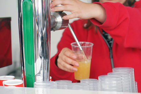 Bartender pouring fresh cold beer from tap, closeup. Female hands pouring beer to plastic glass from tap. worker Girl cafe pours beer into a plastic glass.の写真素材