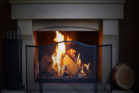 A warm fire in the stone fireplace on a cold night. Warm cozy fireplace with real wood burning in it. Cozy winter concept. Christmas and travel. Christmas backgrounds. Magic burning fireplace.の写真素材