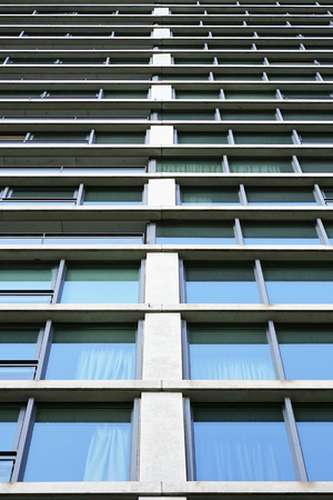 Bottom view glass grey square Windows of modern city business building skyscraper. Receding perspective, movement forward and up. Bottom view of office building window close up.の写真素材