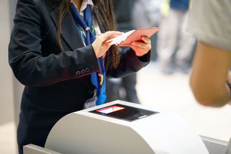 The stewardess checking the documents for boarding the plane at the airport. A female airport employee checks the passport of the passenger. A man in a tourist trip at the airport. Selective focus.の写真素材