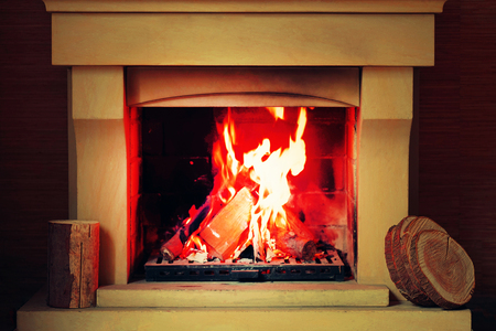 A warm fire in the stone fireplace on a cold night. Warm cozy fireplace with real wood burning in it. Cozy winter concept. Christmas and travel. Christmas backgrounds. Magic burning fireplace. Toningの写真素材