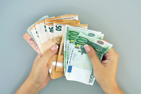 Woman hands that consider 100, 50-euro bills. In the hands of a lot of money, denominations of euros. Businesswoman hands hold and counting euro banknotes.の写真素材
