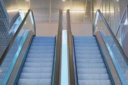 Escalators in an office building. Empty escalator stairs. Modern escalator in shopping mall, Department store escalator. Empty escalator inside a glass building.の写真素材