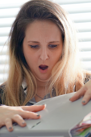 Close-up of office worker is distressed with a lot of paperwork in front of her. A lot of paper work in office. Yelling and screaming for bad results. Businesswoman in problems.の写真素材