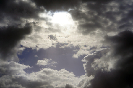 Black rain clouds in the rays of the sun in the sky. Dark clouds the sky.の写真素材