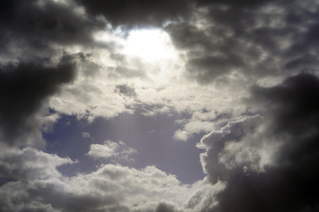 Black rain clouds in the rays of the sun in the sky. Dark clouds the sky.の写真素材