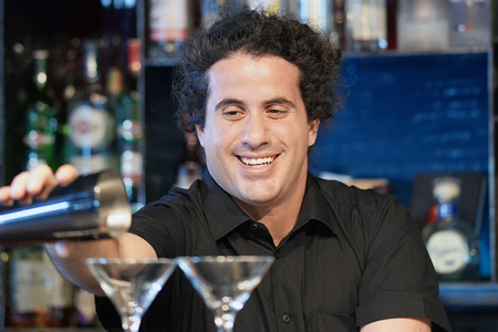Professional barman man pours a fresh cocktail to the customers of the hotel bar. Focus on the bartender. The concept of service. Focus on the bartender.の写真素材