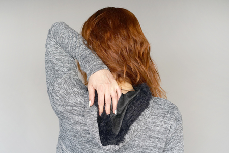 Severe pain in the shoulder of a woman isolated on a gray background.の写真素材