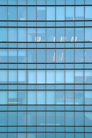 Glass blue square Windows of facade modern city business building skyscraper. Modern apartment buildings in new neighborhood. Windows of a building, texture.の写真素材