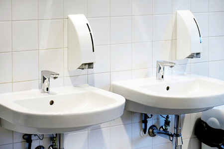 Bathroom interior sink with modern design. Interior of bathroom with washbasin and faucet. Close-up of bathroom. White bathroom. Public bathroom in the airport or restaurant, cafe.の写真素材