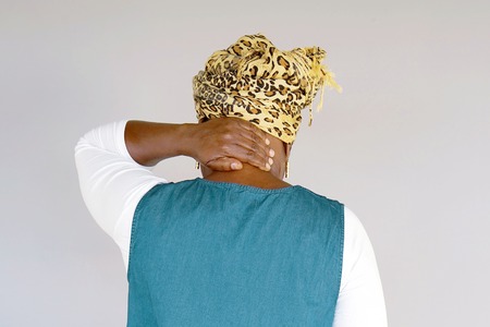 African elderly woman in scarf with pain in the neck isolated on a gray backgroundの写真素材