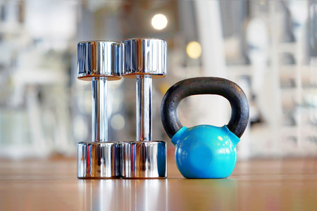 Blue kettlebell and two chrome dumbbell on the floor in the gymの写真素材