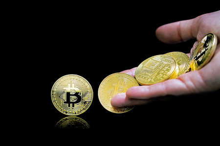 Female palm throws gold bitcoins. Golden bitcoins in female hand. Close-up virtual currency bitcoin...