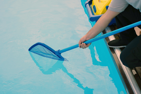 Pool cleaner during his work. Cleaning robot for cleaning the botton of swimming pools. Hotel staff worker cleaning the pool.の写真素材