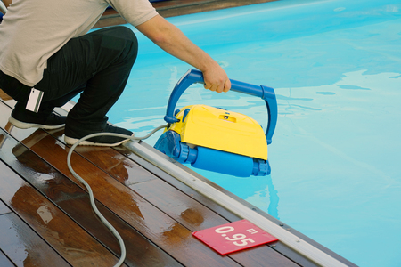 Pool cleaner during his work. Cleaning robot for cleaning the botton of swimming pools. Hotel staff worker cleaning the pool.の写真素材