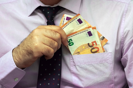 A businessman gives Euro a bribe to an employee in the office. Concept - corruption. Giving a bribe. Money in hand. The concept of corruption and briberyの写真素材