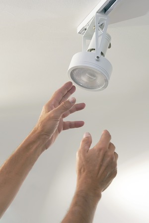 Electric male hand lamps with ceiling LED lamp, spotlight. The concept of repair and maintenance.の写真素材