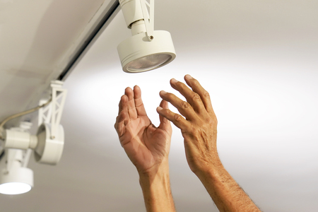 Electric male hand lamps with ceiling LED lamp, spotlight. The concept of repair and maintenance.の写真素材