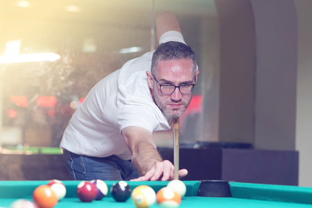 Male plays a billiard at the club. Caucasian mcaucasianan playing spending time on recreation. Play and fun concept. Toningの写真素材