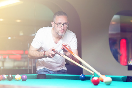 Male plays a billiard at the club. Caucasian mcaucasianan playing spending time on recreation. Play and fun concept. Toningの写真素材