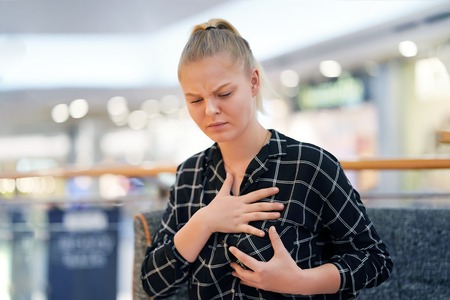 Young girl in blouse having heart attack. Girl, hurts the heartの写真素材