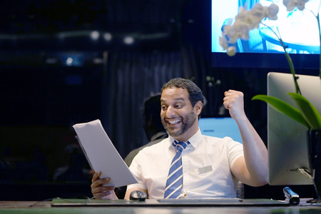 Male reception worker, happy man, enjoying the good news in writing. Hotel administrator. An euphoric male is happy after reading good news in a written letter, approving a loan, raising her job.の写真素材
