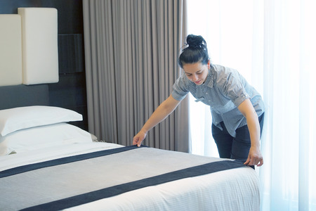Maid making bed in hotel room. Housekeeper Making Bedの写真素材