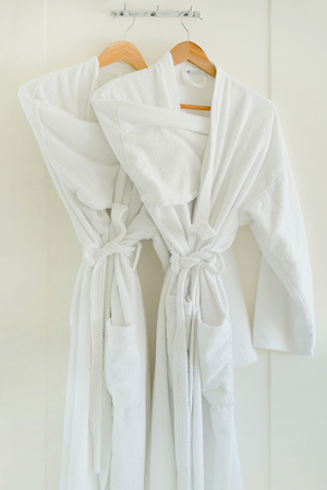 Two white coats hanging on the door. Hotel dressing gowns on the door hanger.の写真素材
